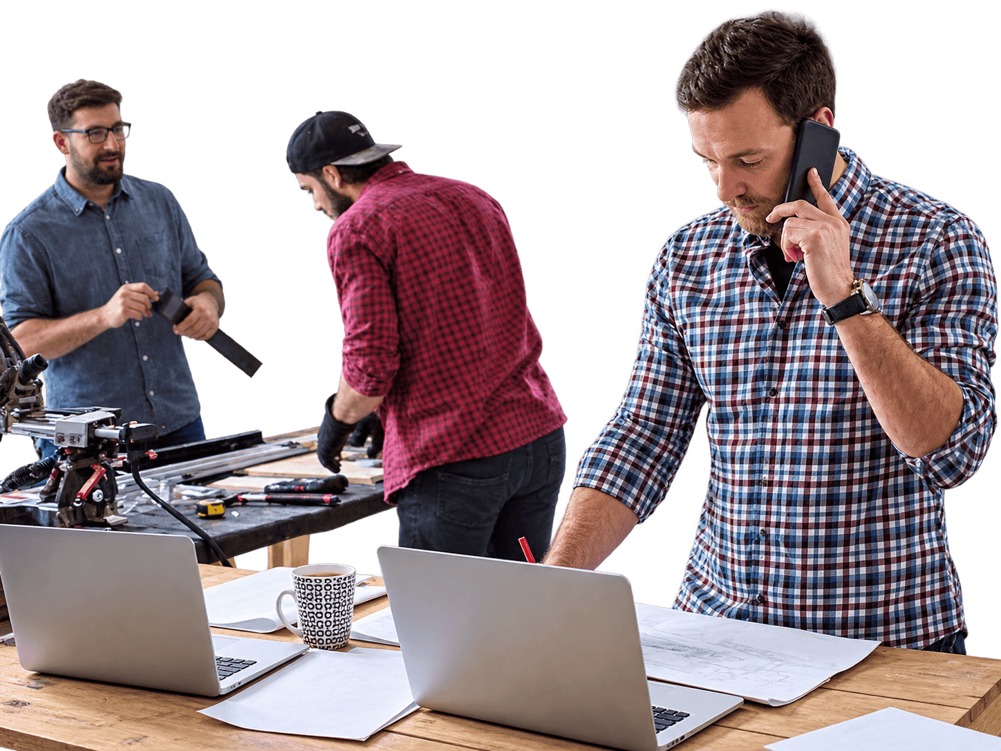 Small-business owners catching up on bookkeeping with laptops and paperwork in their workshop